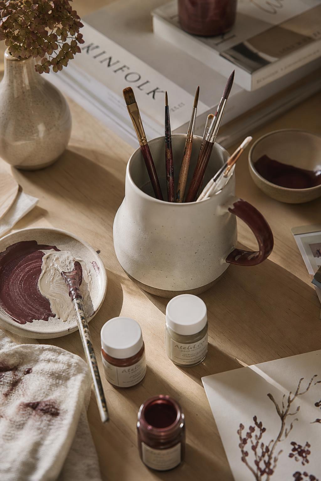 Pincéis, tintas e materiais artísticos sobre uma mesa de madeira
